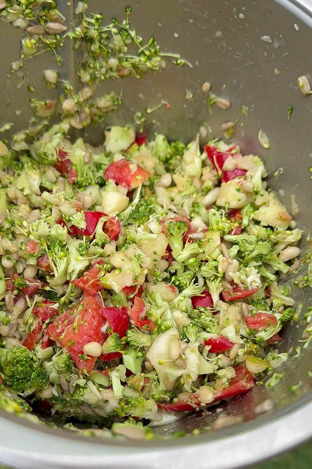 Close-up of chopped broccoli apple salad with pine nuts and red pepper.