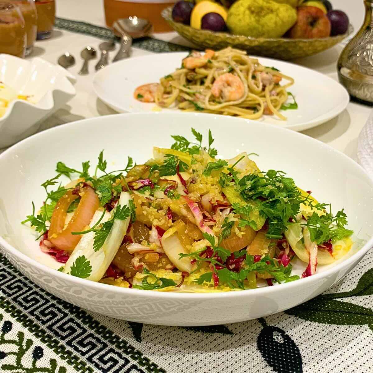 Chicory salad ingredients laid out on marble with clementines pomegranate and fresh chervil.
