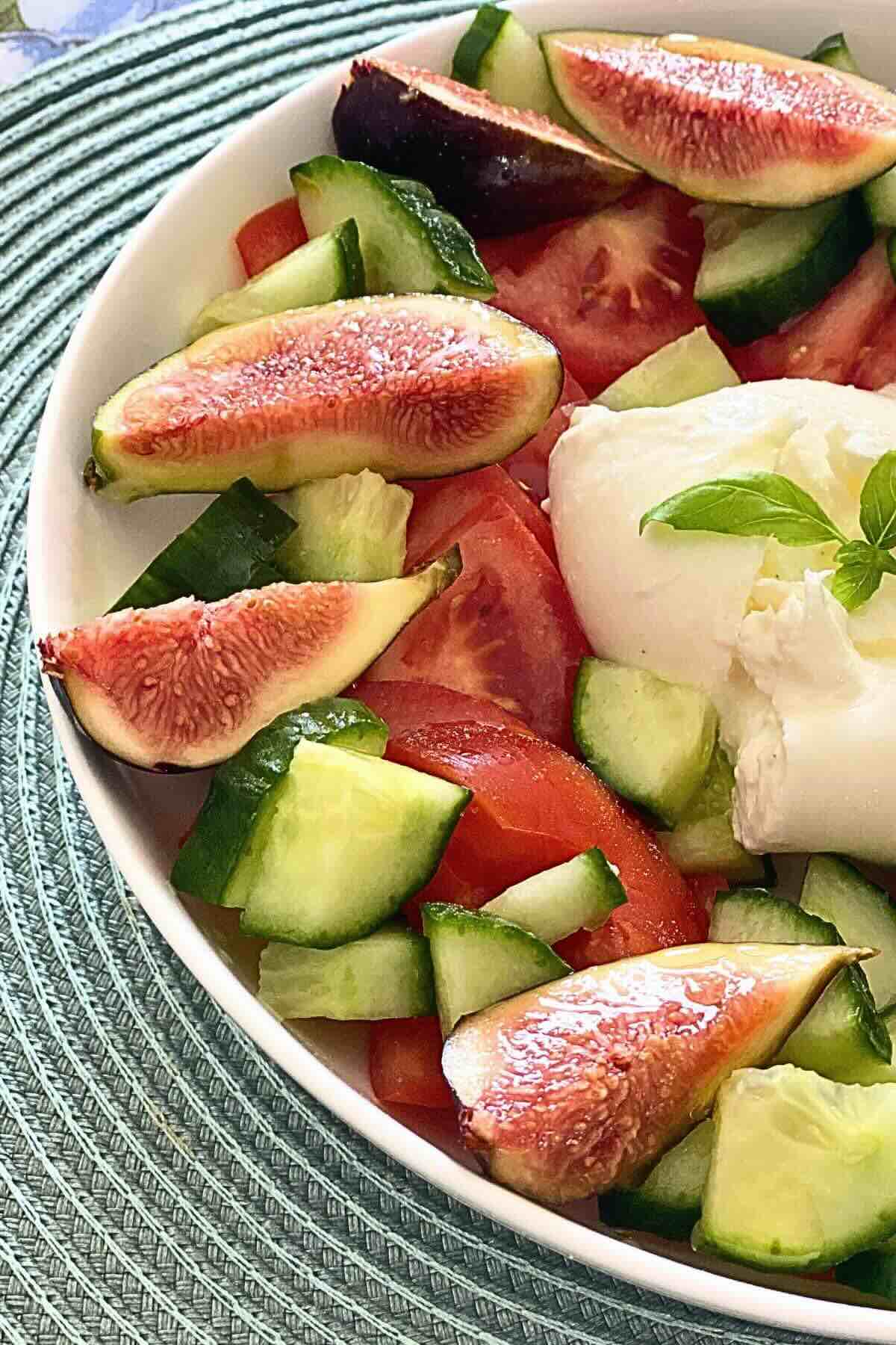 Showcase a fresh burrata caprese salad recipe topped with sliced sweet figs and fresh basil.