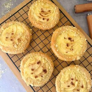 Finished apple custard pastries with powdered sugar on a rack.