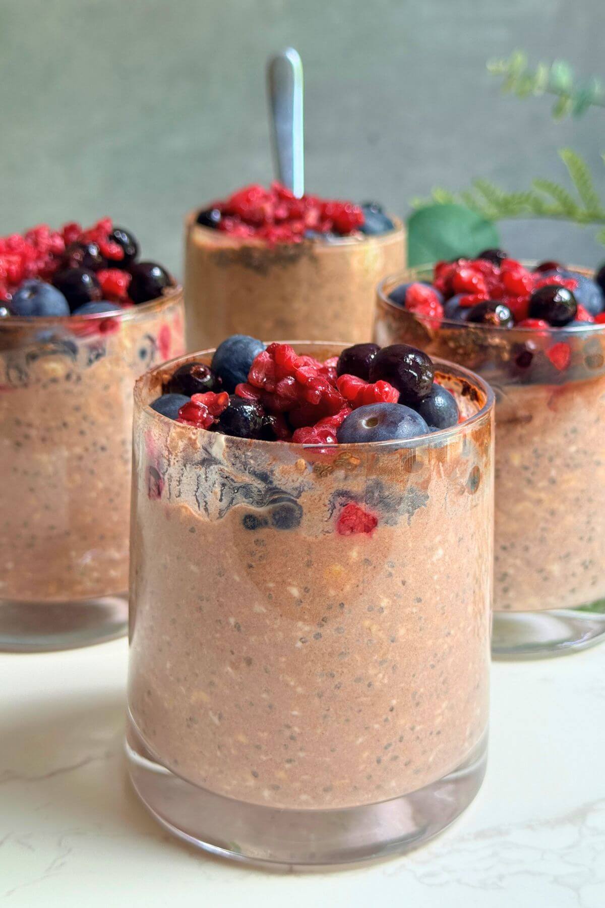 Chocolate berry protein overnight oats served in a glass with fresh mixed berries on top.