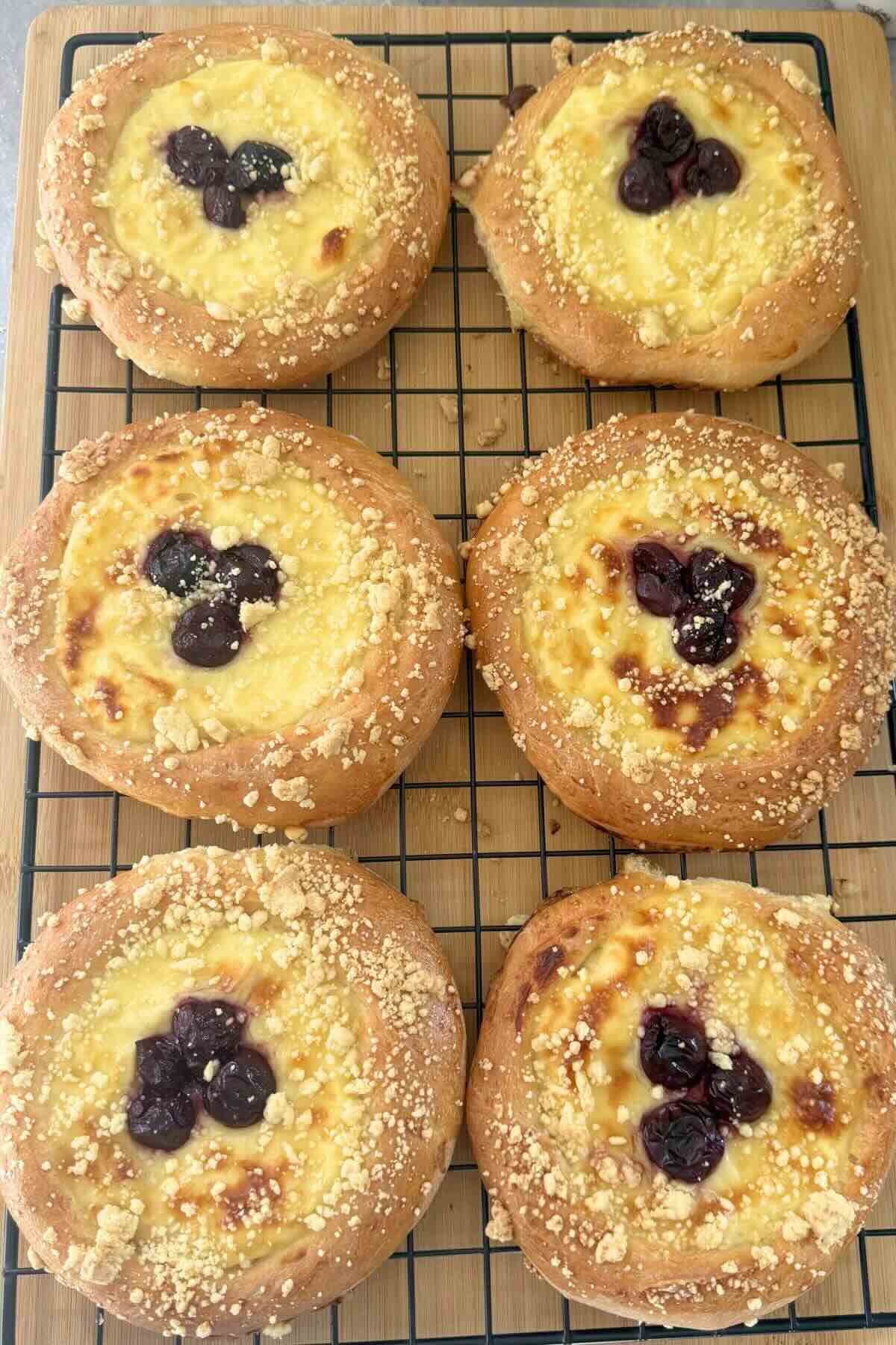 Finished cherry custard pastries with powdered sugar on a rack.