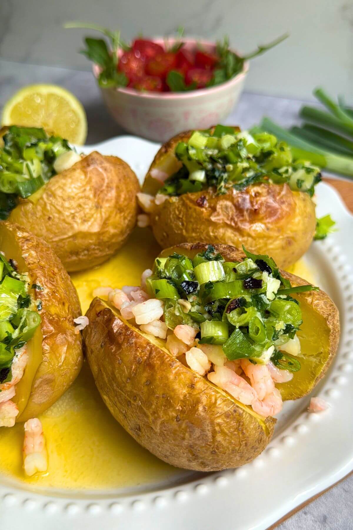 Plated baked potato with shrimp arugula and cherry tomatoes.