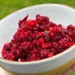 Simple beetroot salad with apple and carrot in a bowl with fresh herbs.