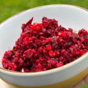 Simple beetroot salad with apple and carrot in a bowl with fresh herbs.