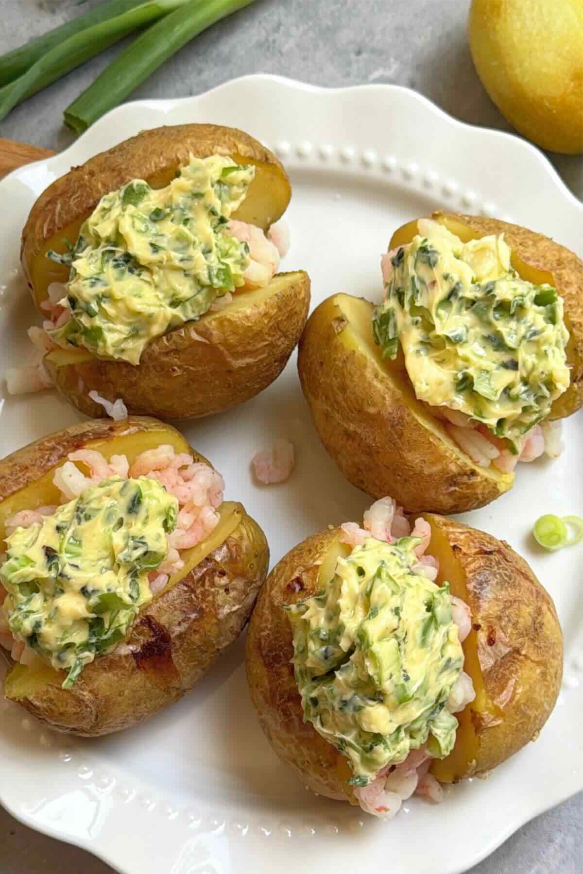Baked potato split open topped with garlic butter shrimp and lemon.