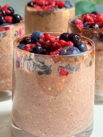 Chocolate berry protein overnight oats served in a glass with fresh mixed berries on top.