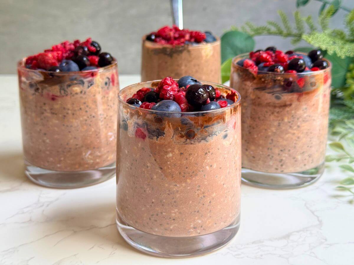 Chocolate berry protein overnight oats served in a glass with fresh mixed berries on top.