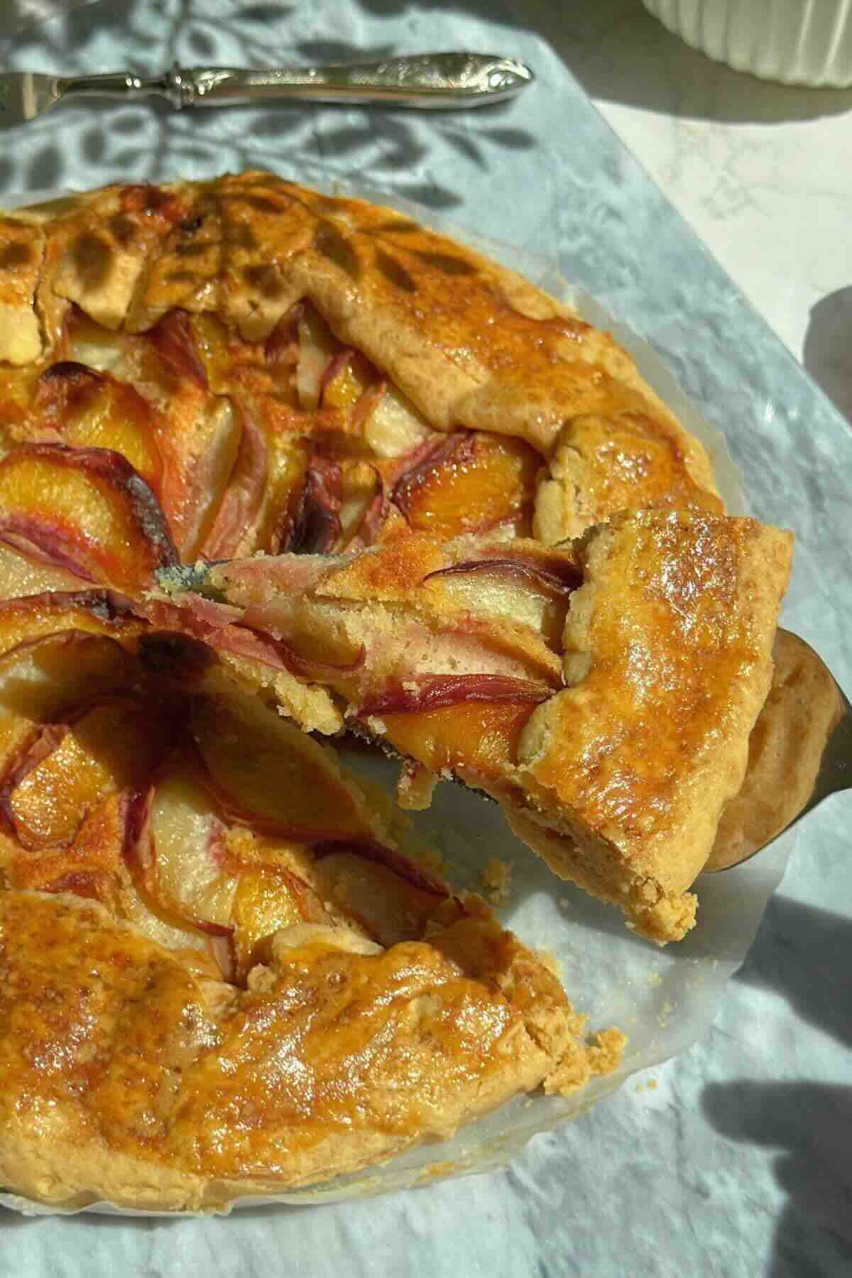 Golden peach galette with brown sugar crust, sliced open to show almond filling and peaches.