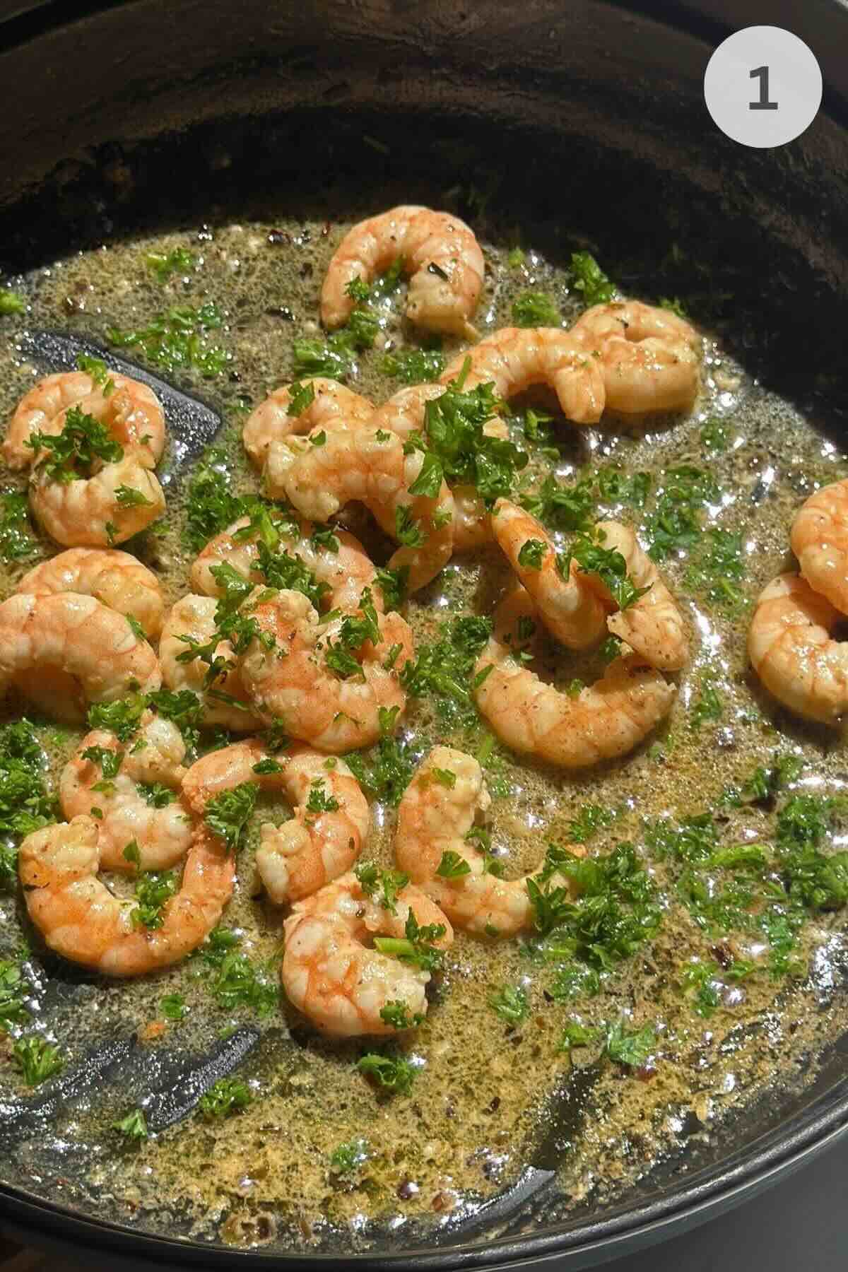Shrimp cooking in smoked paprika garlic butter in large pan.