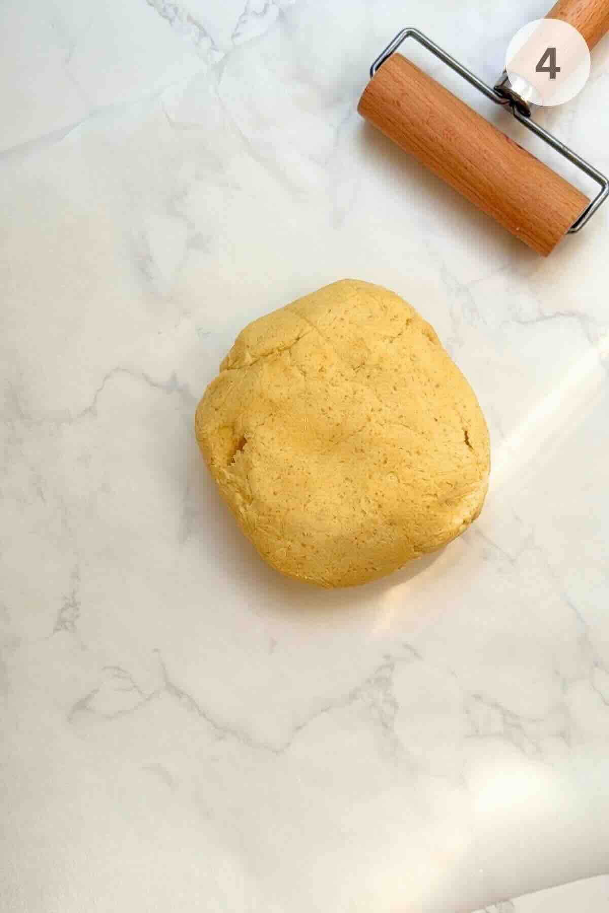 Displaying a smooth pastry dough resting on parchment paper ready to be rolled.