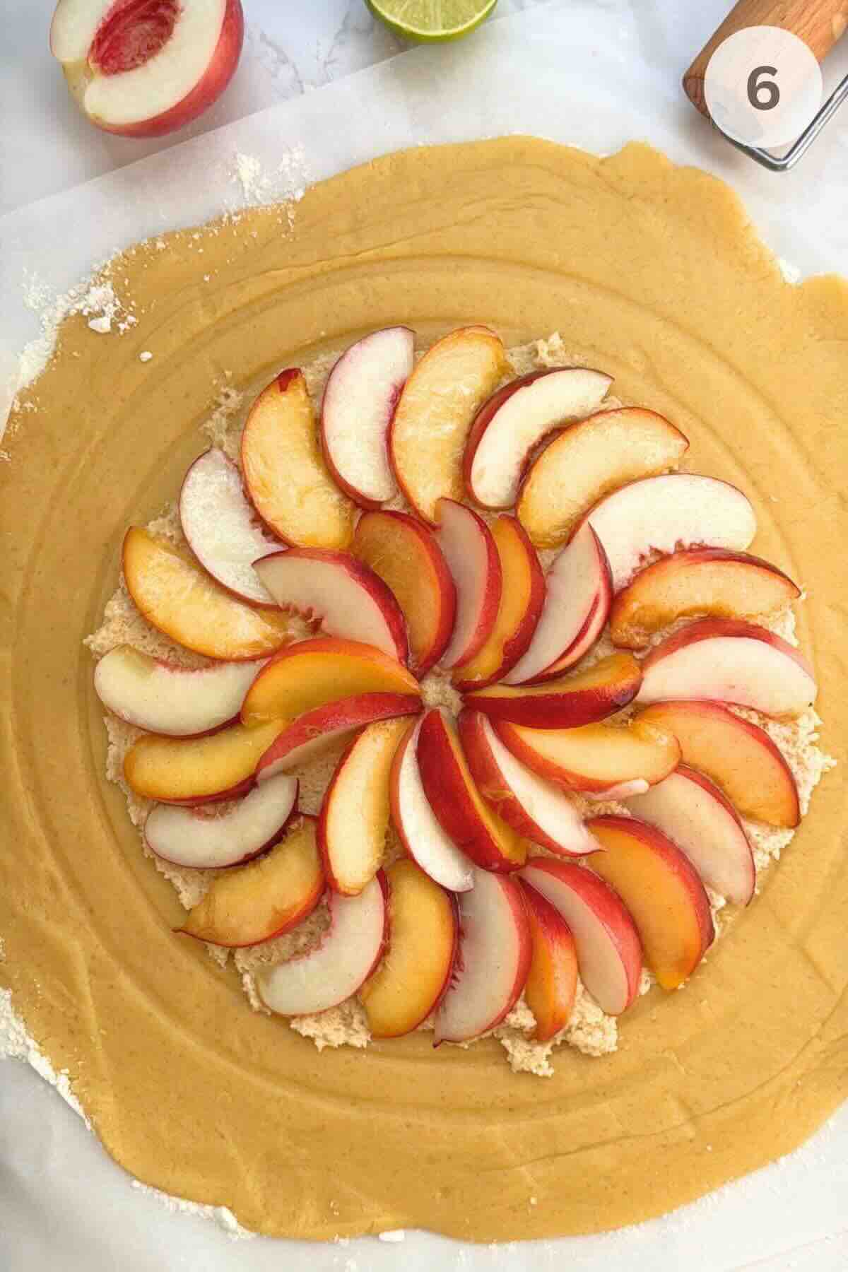 Showing folded pastry edges wrapped around a center layer of frangipane and fresh peaches.