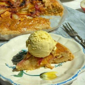 Golden peach galette with brown sugar crust, sliced open to show almond filling and peaches, served with a scoop of vanilla ice cream.