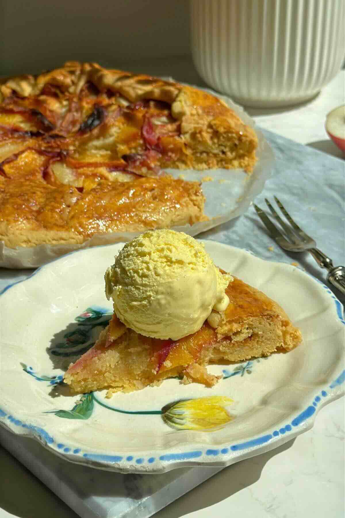 Golden peach galette with brown sugar crust, sliced open to show almond filling and peaches, served with a scoop of vanilla ice cream.