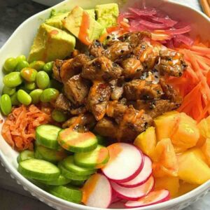 Cooked tuna poke bowl with seared tuna, sushi rice, avocado, and mango in a bowl.