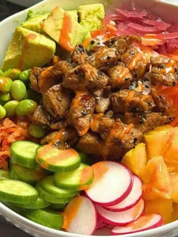 Cooked tuna poke bowl with seared tuna, sushi rice, avocado, and mango in a bowl.