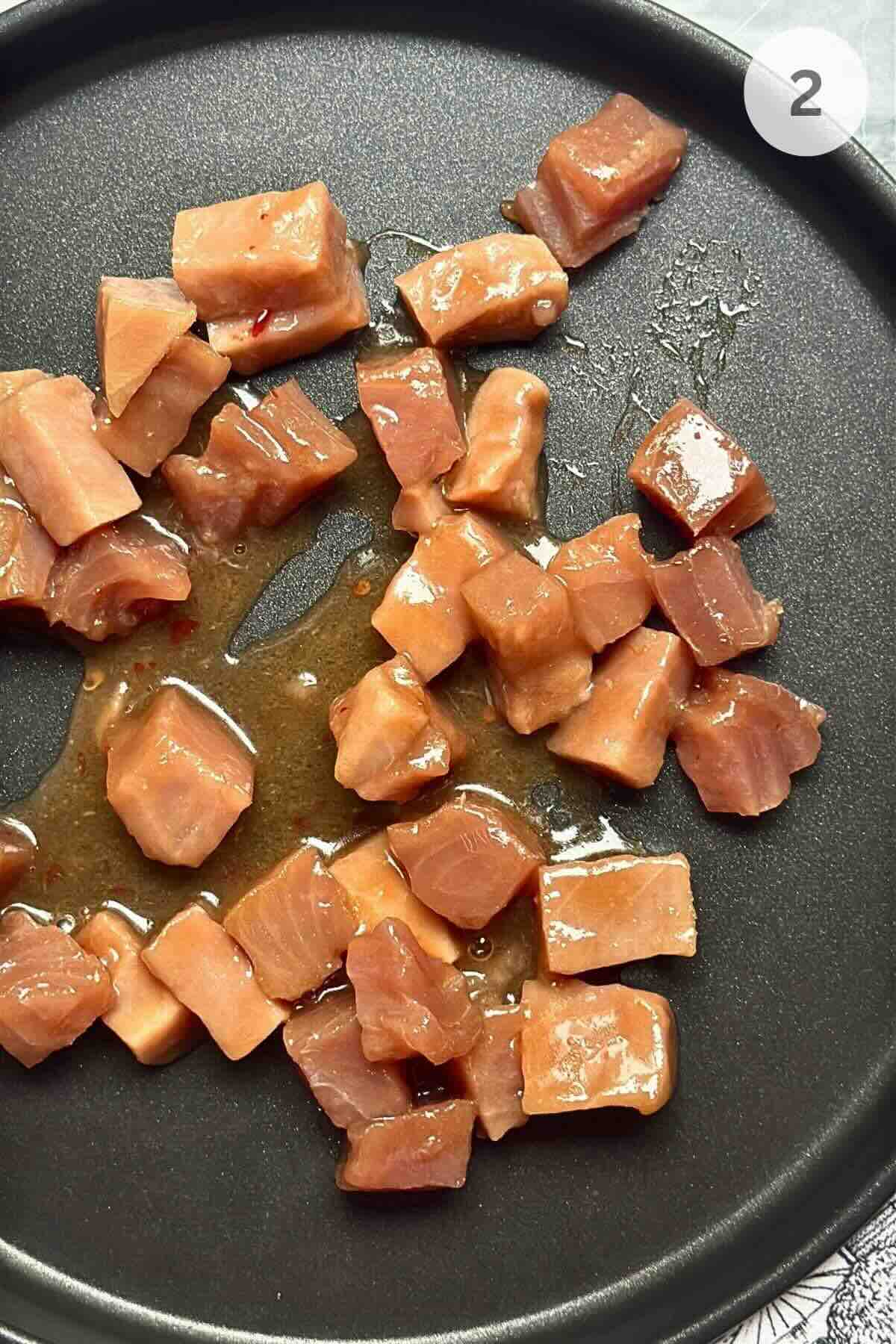 Searing seasoned tuna cubes in a hot skillet for a quick, golden crust.