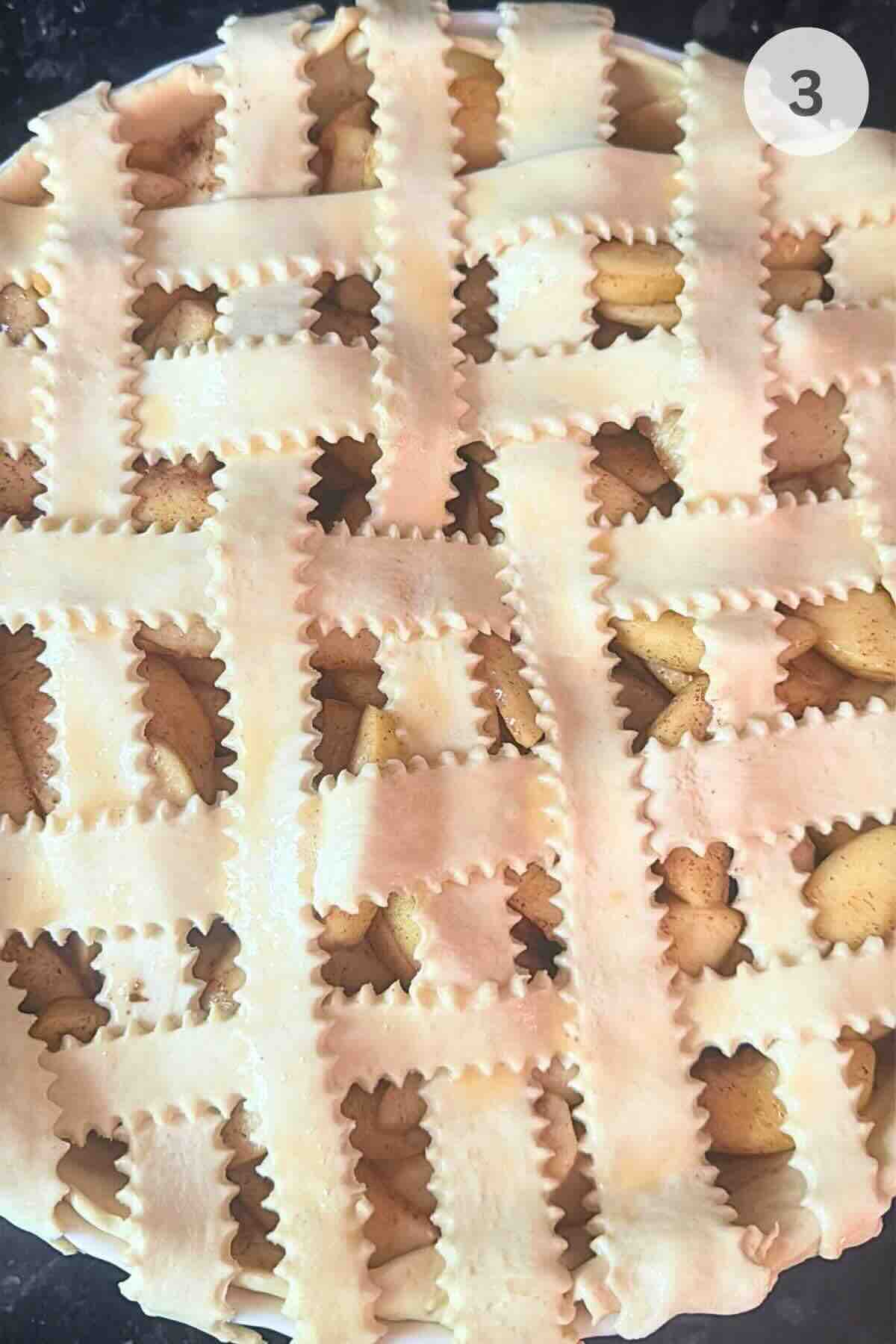 Puff pastry lattice strips arranged over apple pie filling.