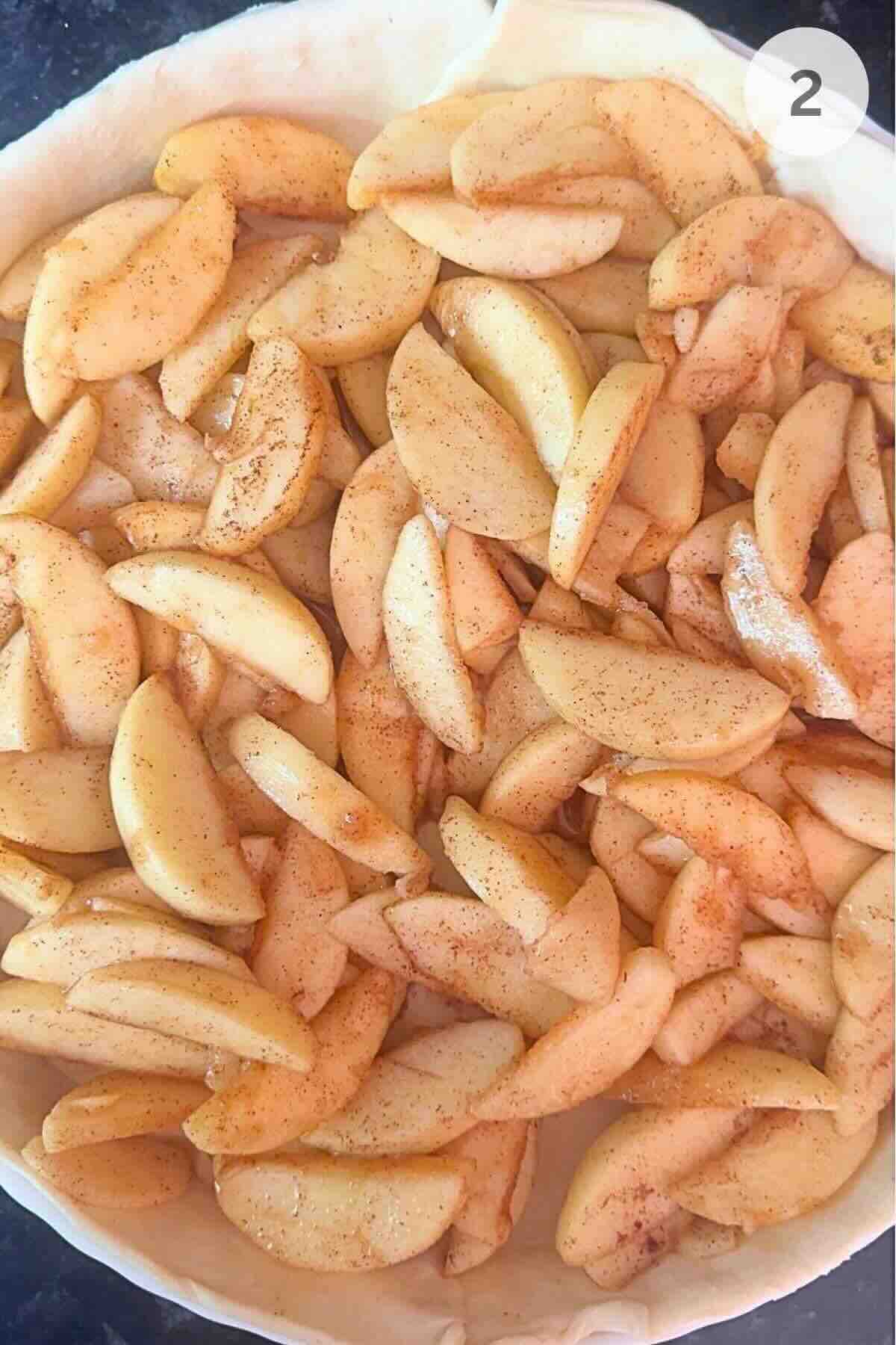 Puff pastry pressed into pie dish filled with spiced apple slices.