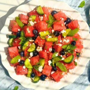 Watermelon cucumber feta salad with mint and lime dressing in a white bowl.