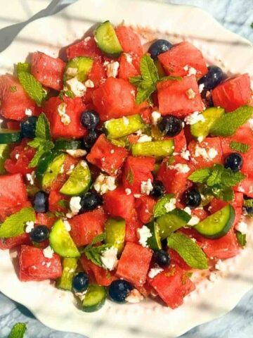 Watermelon cucumber feta salad with mint and lime dressing in a white bowl.