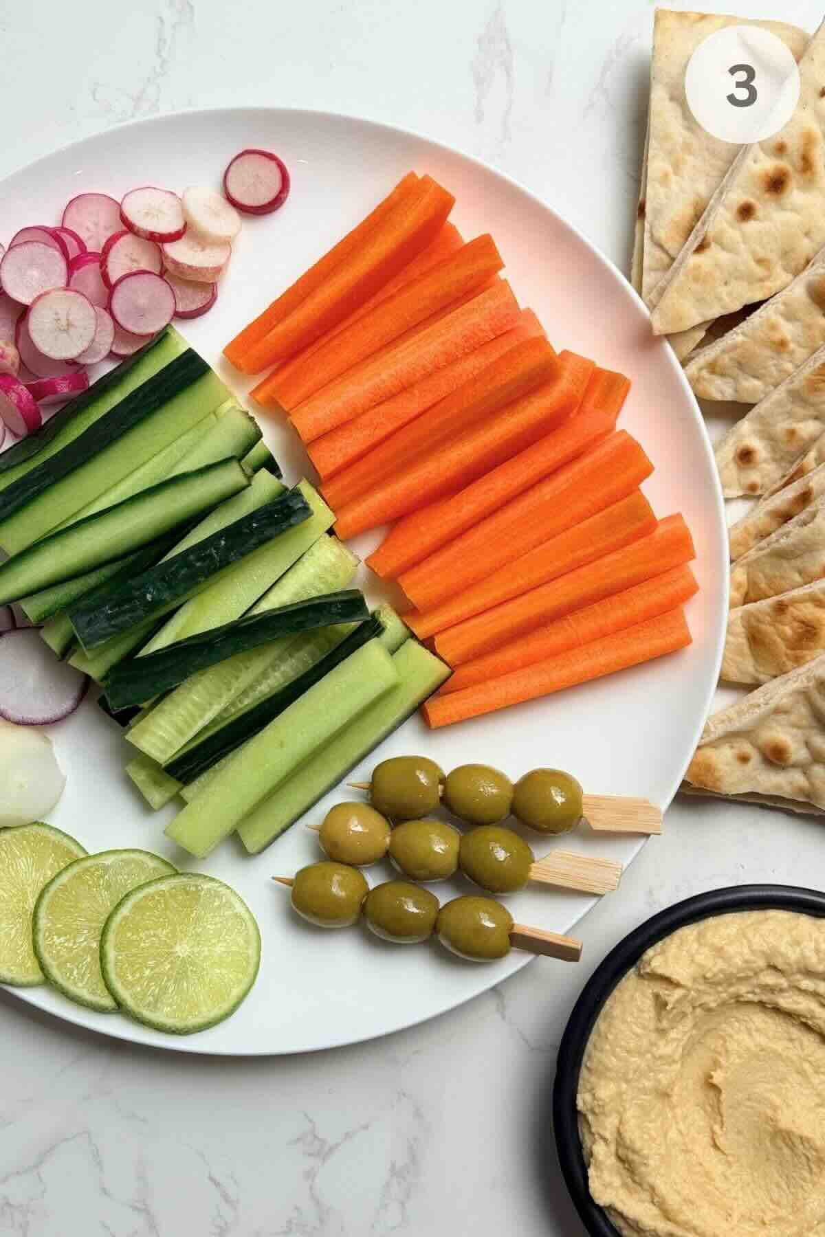 Sliced cucumber sticks, carrot sticks, and halved radishes drizzled with fresh lime juice on a board.