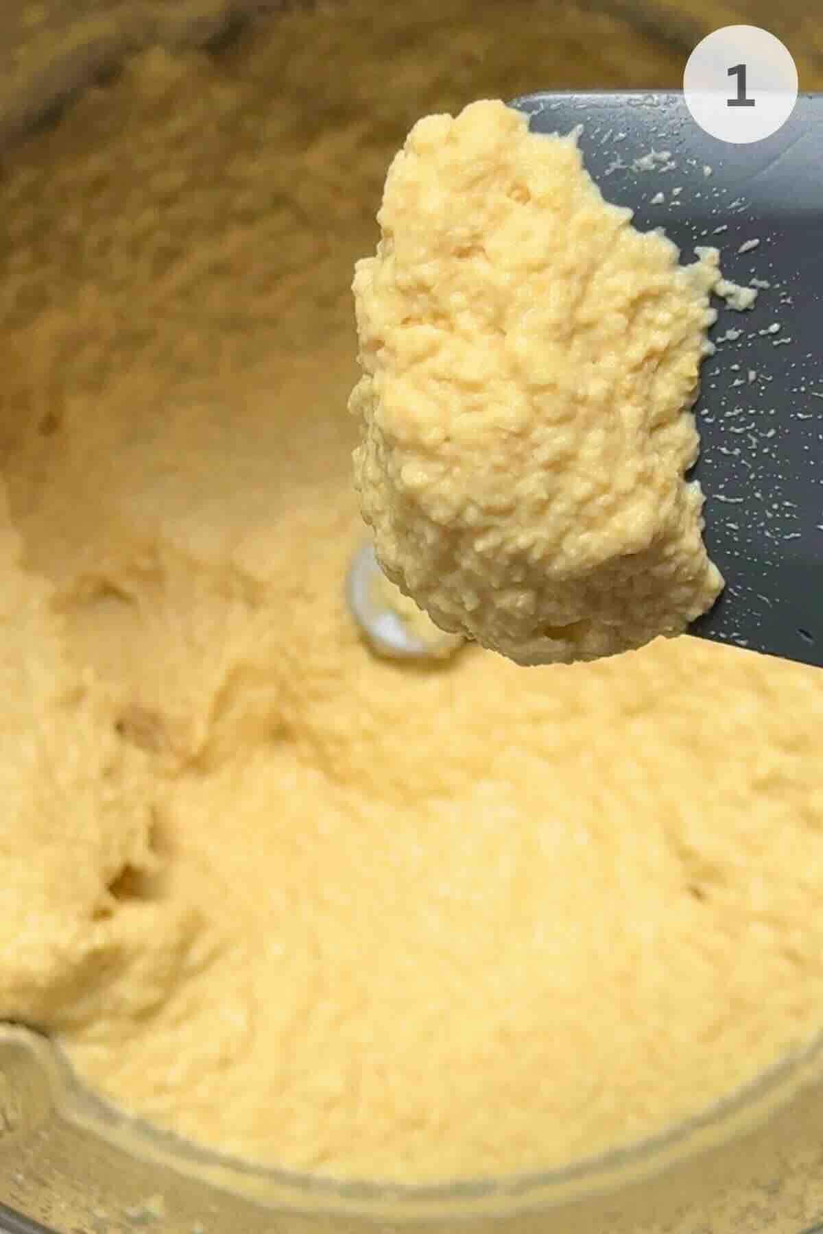 Blending fresh garlic, chickpeas, lemon juice, olive oil, and cold water in a food processor.