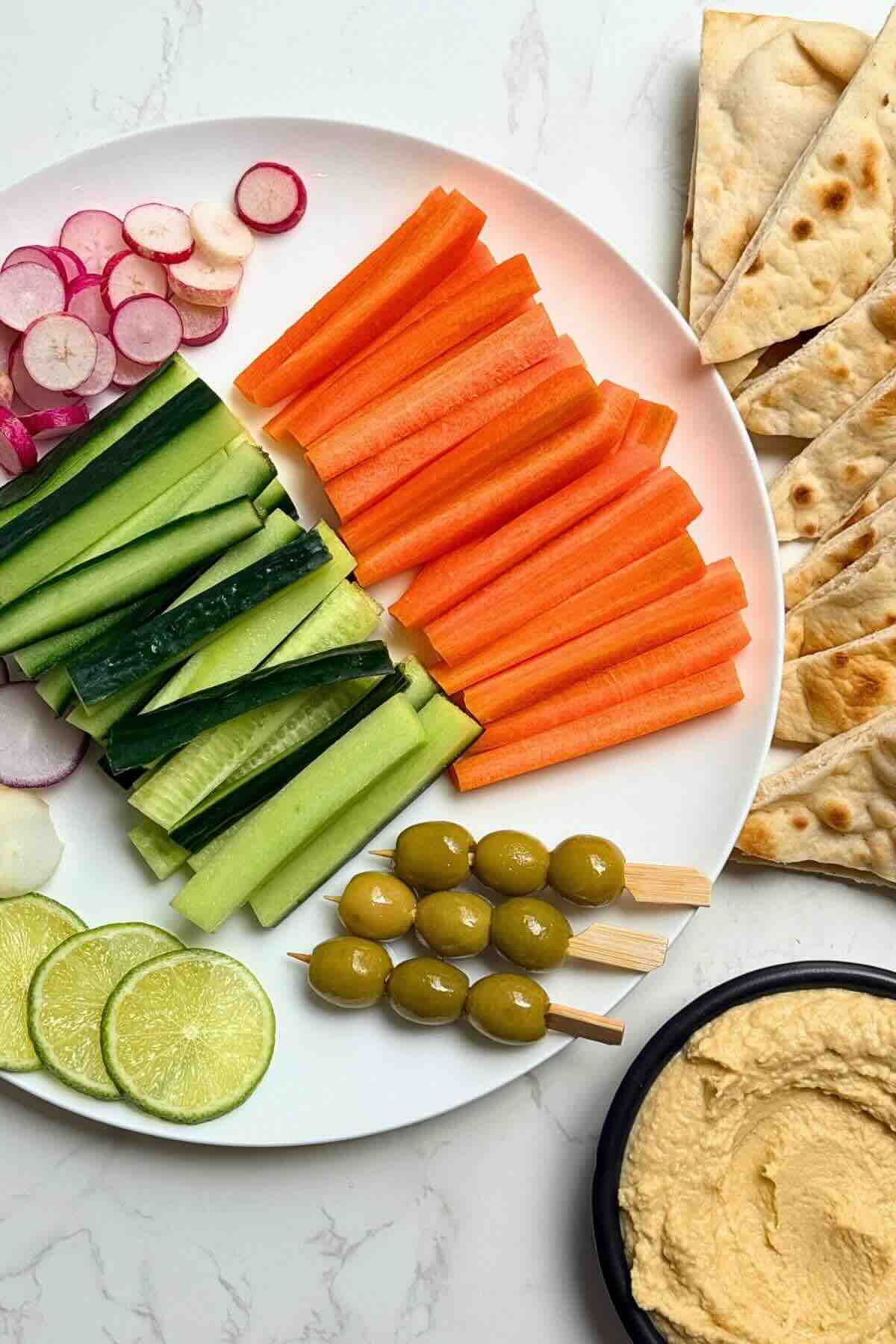Slicing fresh cucumbers, carrots, and radishes on a cutting board with lime juice.
