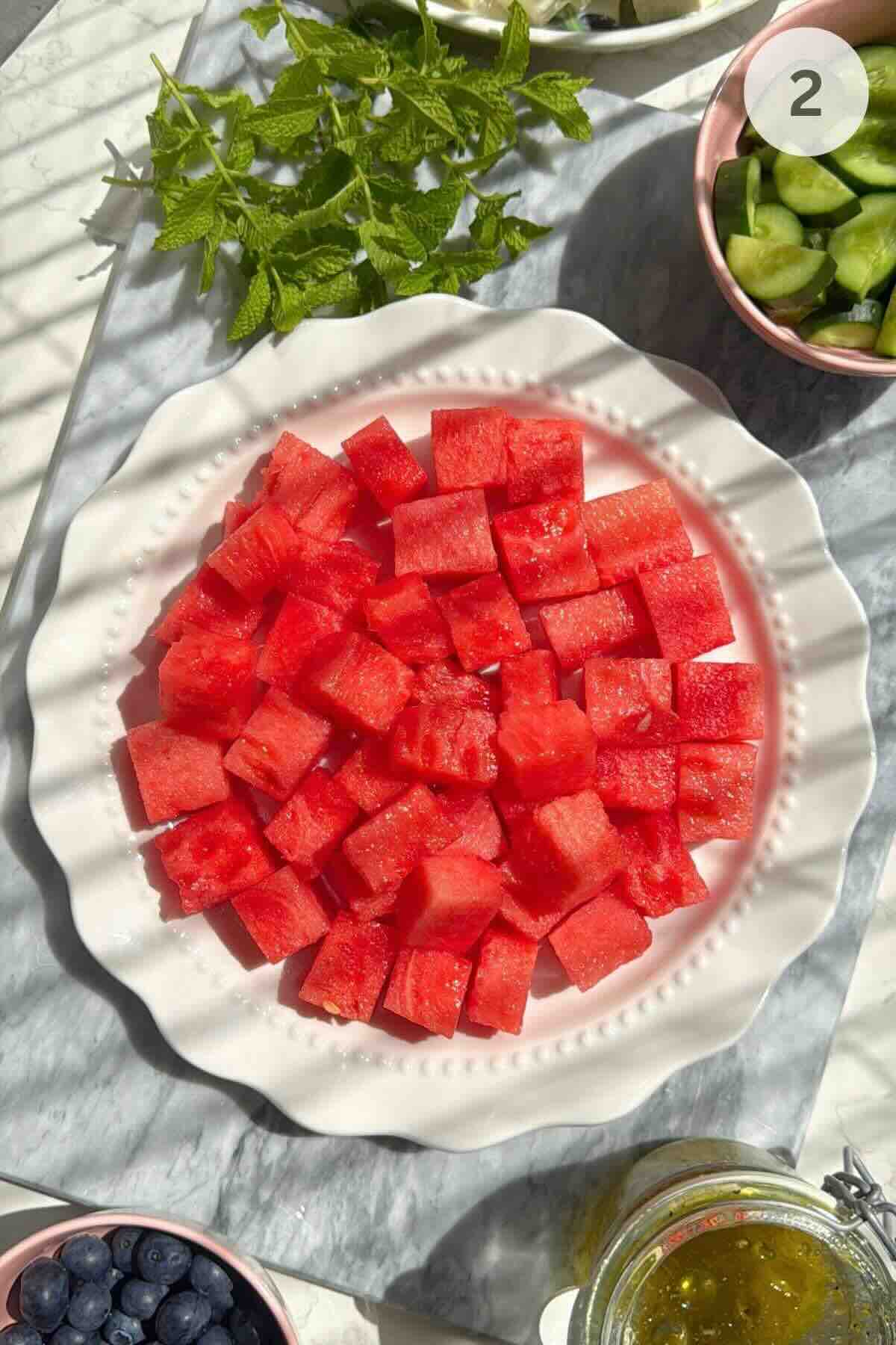 Fresh watermelon, cucumber, blueberries, feta, and mint prepared for salad.