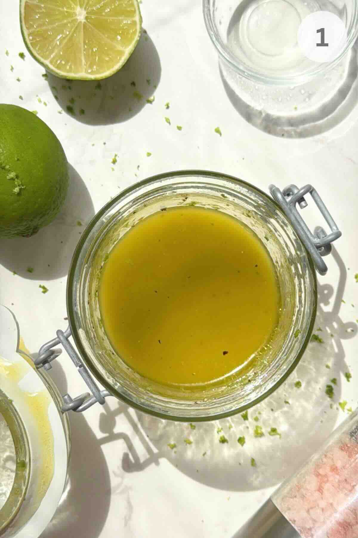 Lime dressing ingredients mixed in a glass jar for watermelon cucumber feta salad.