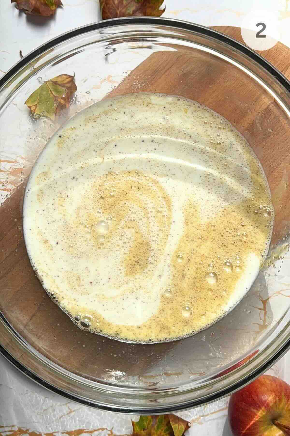 Smooth cinnamon custard in a shallow dish with a whisk on the side.
