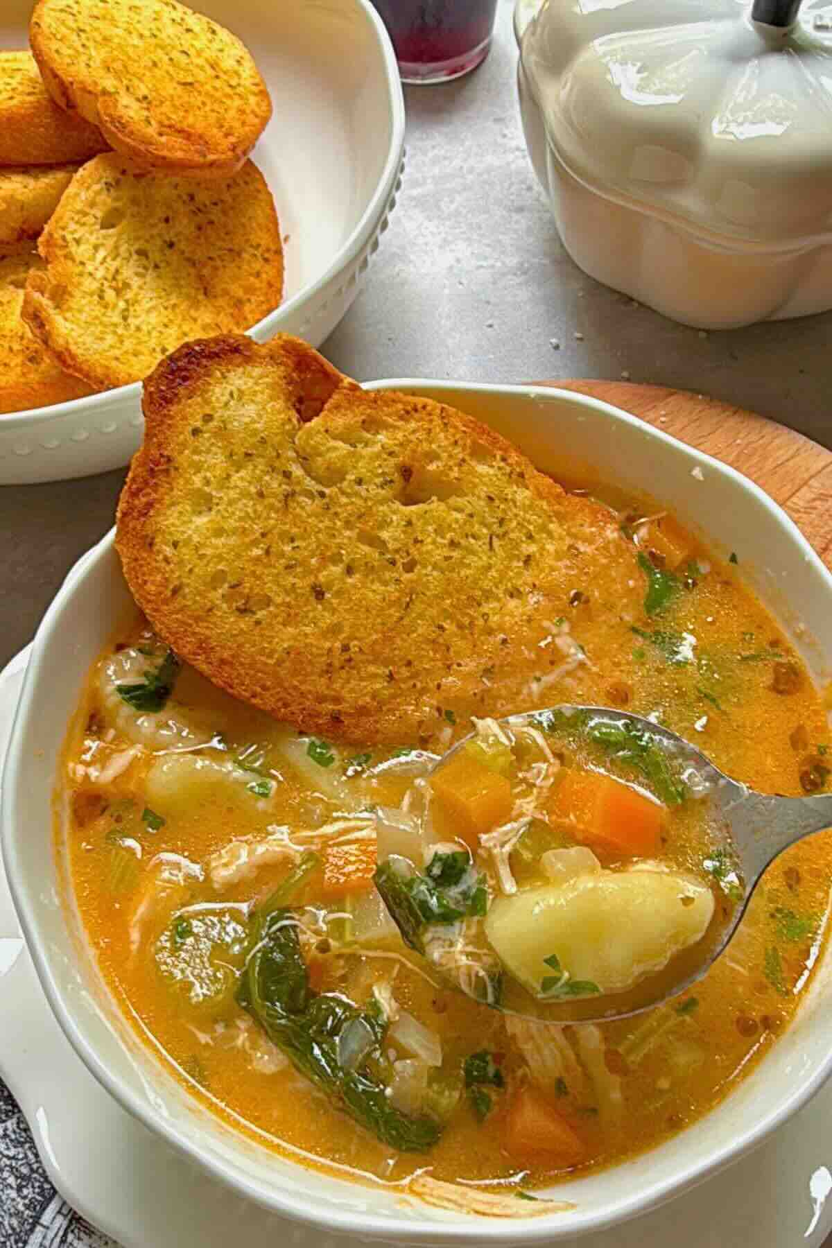 Bowl of creamy chicken gnocchi vegetable soup with parsley garnish.
