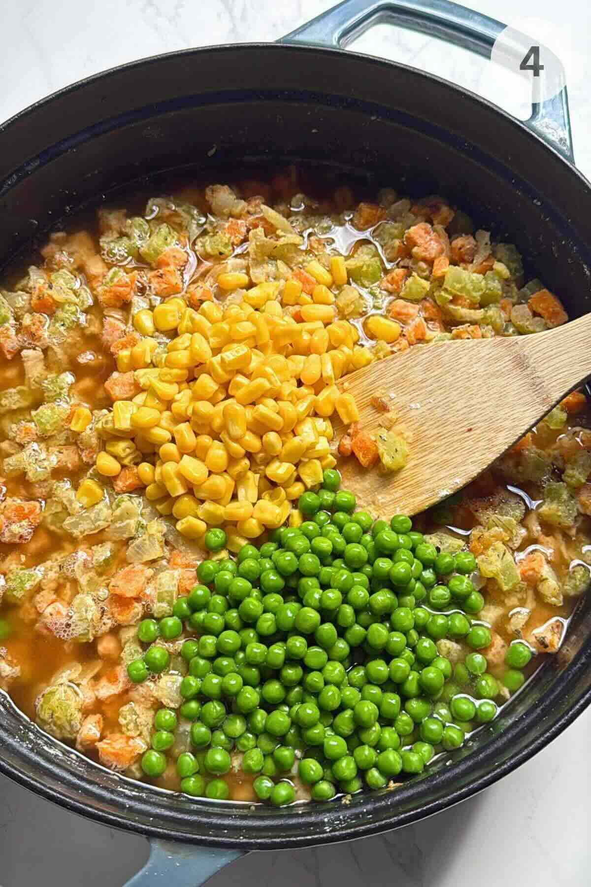 Chicken broth, corn, and peas being stirred into the sautéed vegetable mixture.