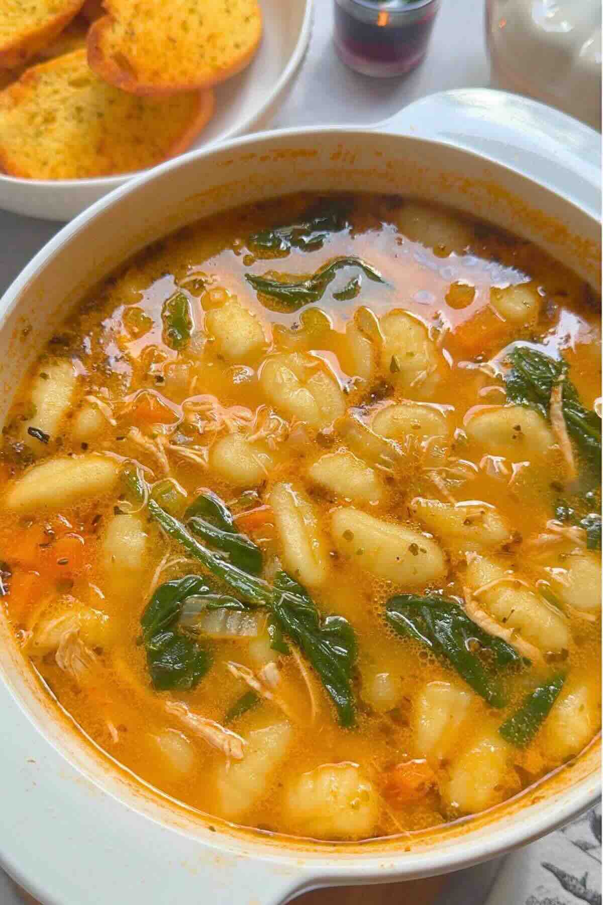 Bowl of creamy chicken gnocchi vegetable soup with parsley garnish.