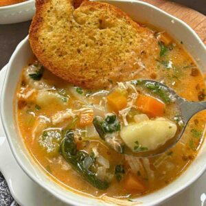 Bowl of creamy chicken gnocchi vegetable soup with parsley garnish.