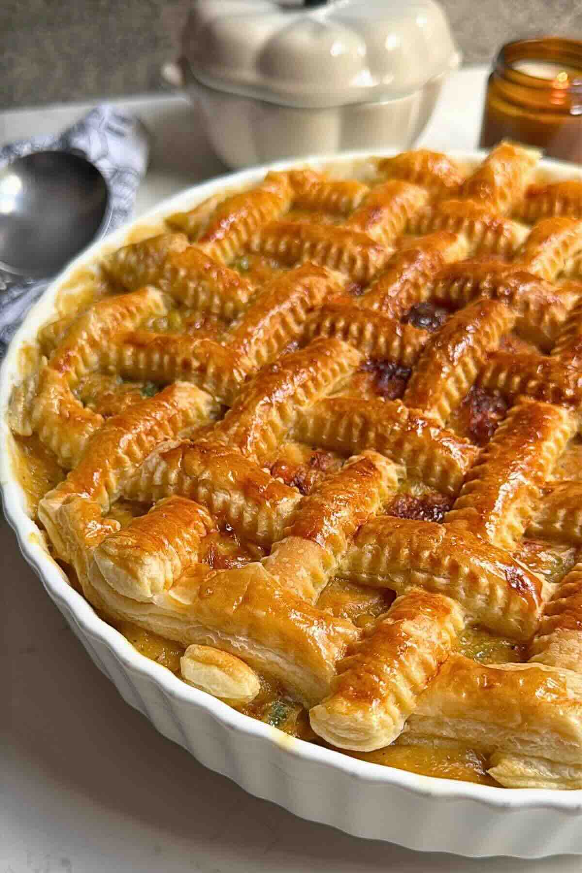 Braided puff pastry chicken pot pie in a ceramic dish, golden and crisp on top.