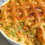 Braided puff pastry chicken pot pie in a ceramic dish, golden and crisp on top.