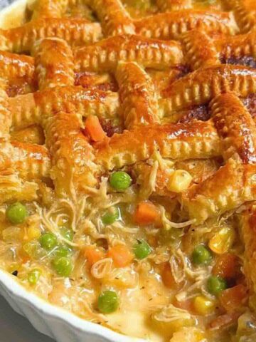 Braided puff pastry chicken pot pie in a ceramic dish, golden and crisp on top.