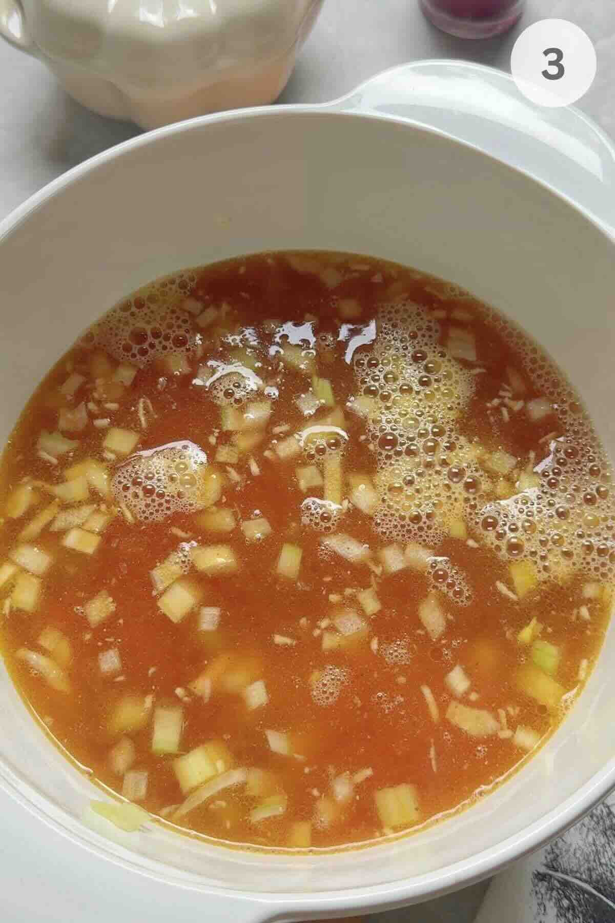 Chicken stock and cream being poured into a pot of sautéed vegetables.