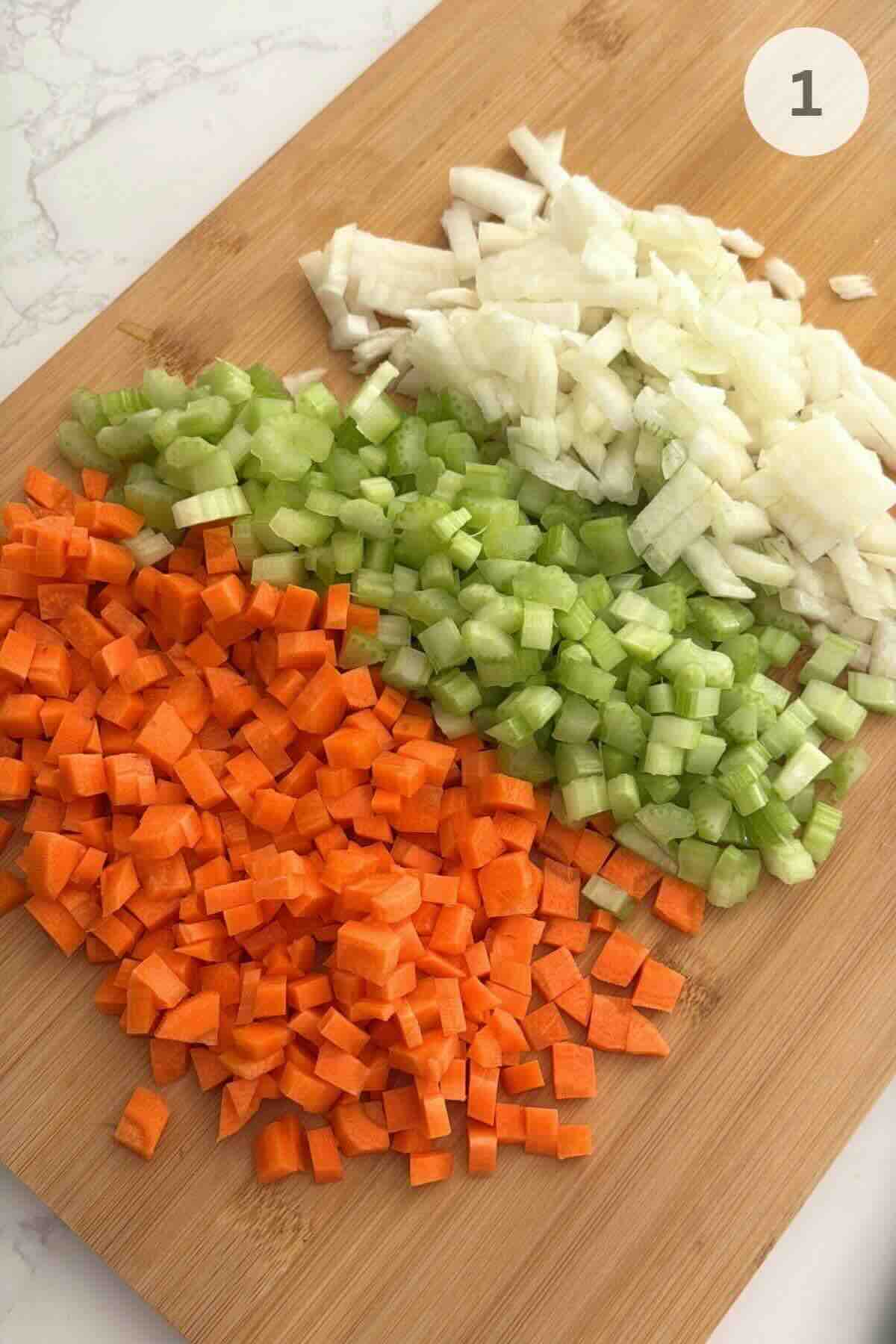 Diced onion, carrots, and celery on a cutting board for chicken gnocchi soup.
