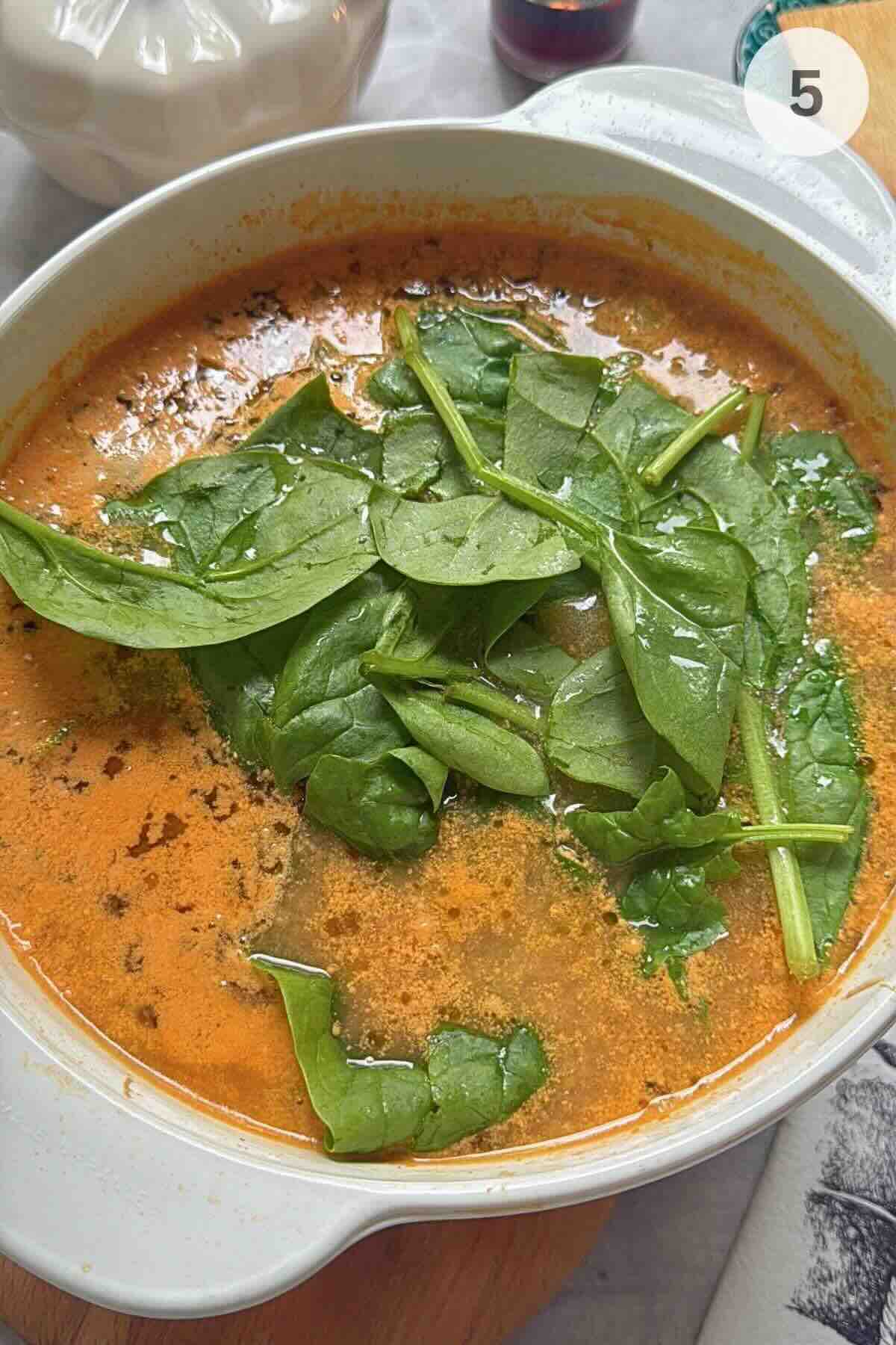 Gnocchi and spinach added to a pot of creamy chicken vegetable soup.
